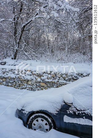 Front Half of Dark Car Covered in Snow on Winter Road 135611612