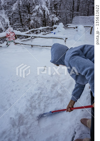 Woman Removing Snow with Mop, Face Not Visible 135611622