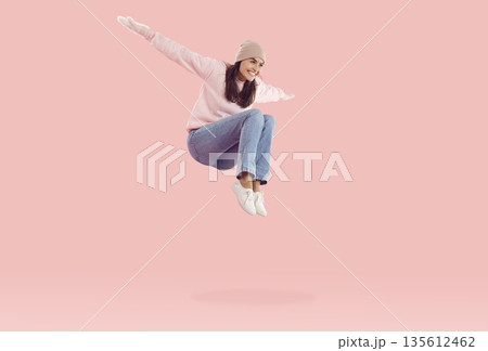 Funny young woman in winter mittens and hat laughing and having fun jumping high. Funny young woman in winter mittens and hat laughing and having fun jumping high. 135612462