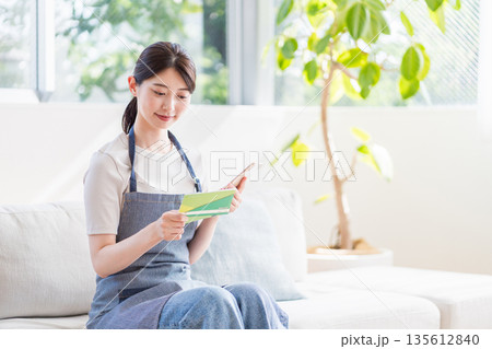 通帳を確認する若い主婦。 135612840