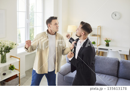 Two men facing off in tense argument with raised fists, threatening physical fight Two men facing off in tense argument with raised fists, threatening physical fight 135613178