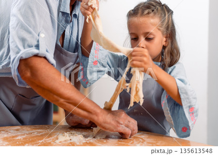 Grandmother and granddaughter making dough 135613548