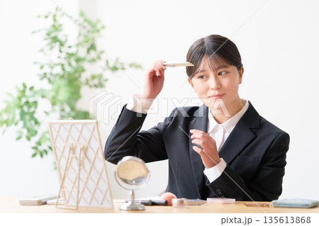 鏡を見ながらコームで前髪を整えて身だしなみチェックをするリクルートスーツ姿の女性 鏡を見ながらコームで前髪を整えて身だしなみチェックをするリクルートスーツ姿の女性 135613868