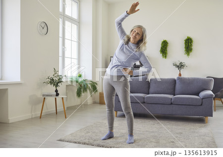 Happy senior woman doing physical exercise, side bends and stretching workout Happy senior woman doing physical exercise, side bends and stretching workout 135613915