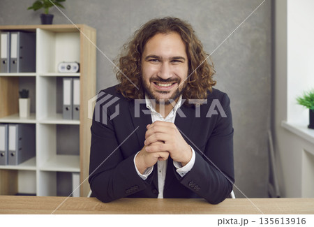 Portrait of happy, smiling businessman sitting in office and attending work meeting via video call Portrait of happy, smiling businessman sitting in office and attending work meeting via video call 135613916