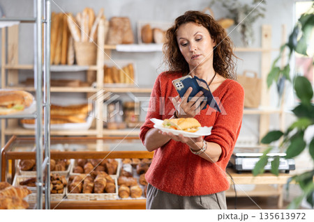Woman capturing a sandwich photo in a bakery Woman capturing a sandwich photo in a bakery 135613972
