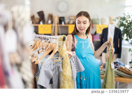 Pregnant woman choosing clothes Pregnant woman choosing clothes 135613977