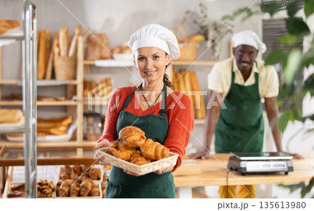 Portrait of joyful woman baker with croissants 135613980