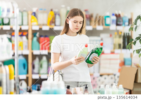 Female shopper selects dishwashing in the household goods section of supermarket 135614034