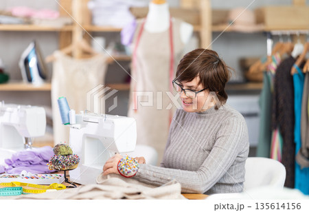 Woman tailor sews clothes in sewing machine Woman tailor sews clothes in sewing machine 135614156