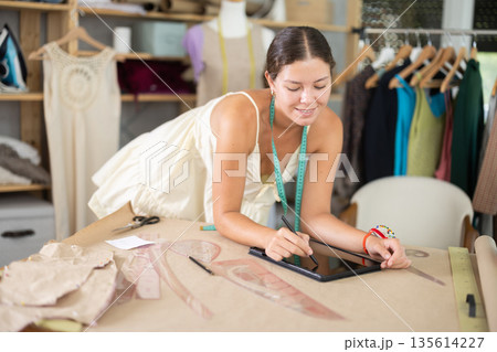 Female tailor create sketch of dress in tablet Female tailor create sketch of dress in tablet 135614227