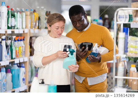Couple man and woman scanning qr code for cleaning spray Couple man and woman scanning qr code for cleaning spray 135614269