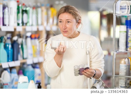 Female shopper chooses scented candles in supermarket for romantic evening 135614363