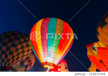 colorful hot air balloons glowing against dark night sky 135615744