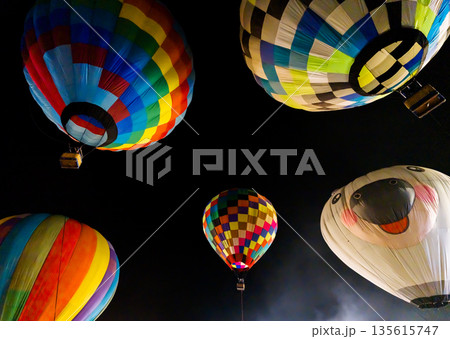 colorful hot air balloons glowing against dark night sky colorful hot air balloons glowing against dark night sky 135615747