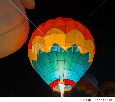 colorful hot air balloons glowing against dark night sky colorful hot air balloons glowing against dark night sky 135615756