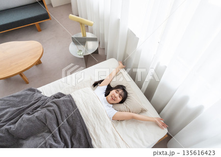 ベッドで伸びをする女性 135616423