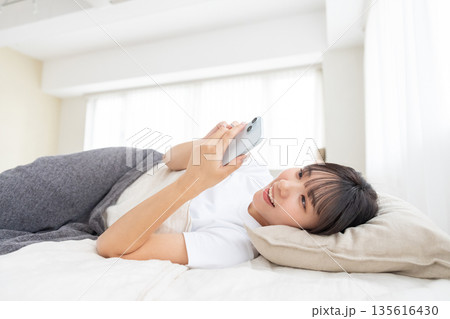 ベッドでスマホを操作する若い女性 135616430