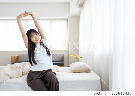 ベッドで伸びをする女性 135616439