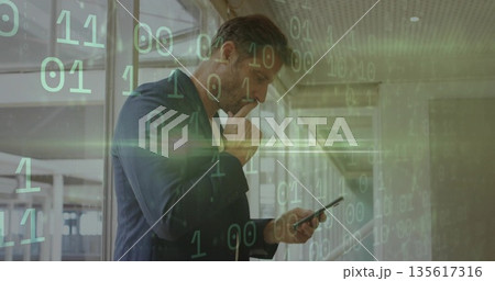 Standing executive holding smartphone and thinking in glass office corridor, with binary code Standing executive holding smartphone and thinking in glass office corridor, with binary code 135617316