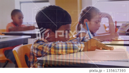 Writing focused boy working in notebook on orange chair in classroom, with pencils, chart overlays Writing focused boy working in notebook on orange chair in classroom, with pencils, chart overlays 135617393