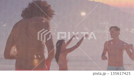 Standing three friends wearing bikini, trunks in water on sunset beach, with paddle skyline overlay Standing three friends wearing bikini, trunks in water on sunset beach, with paddle skyline overlay 135617425