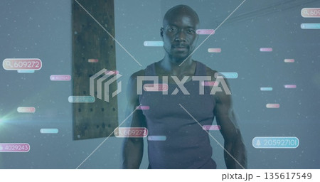 Standing athletic man wearing tank top in studio, with floating numeric overlays and wooden beam 135617549