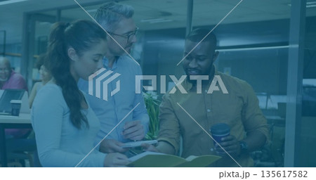 Three colleagues reviewing printed docs in workspace wearing casual attire, with coffee cup, plant Three colleagues reviewing printed docs in workspace wearing casual attire, with coffee cup, plant 135617582