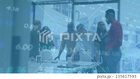Reviewing professionals in business attire studying charts and floating figures on table in office Reviewing professionals in business attire studying charts and floating figures on table in office 135617593