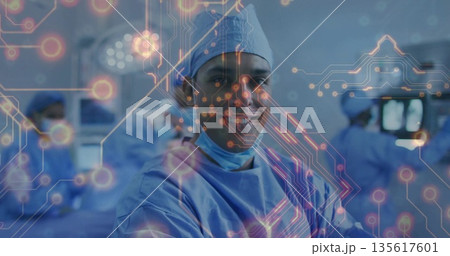 Performing surgery surgeon in blue scrubs monitoring operating table and digital overlay at OR 135617601