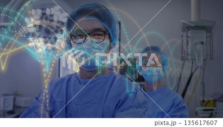 Monitoring vitals masked surgeons watching waveform in operating room, with surgical lamp, monitors 135617607