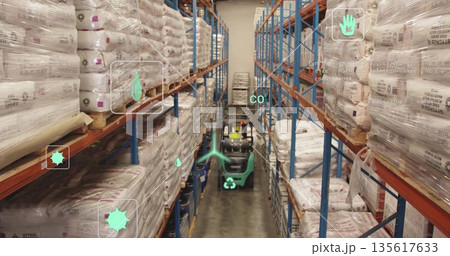 Driving forklift wearing yellow hard hat and vest through aisle, with stacked sacks and shelves Driving forklift wearing yellow hard hat and vest through aisle, with stacked sacks and shelves 135617633