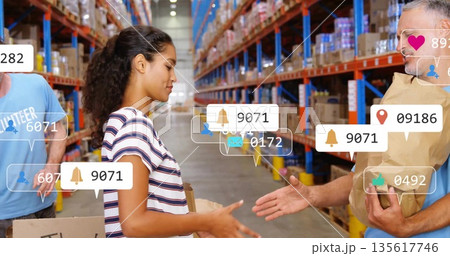 Handing female volunteer passing package to man in warehouse, with notification icons, copy space Handing female volunteer passing package to man in warehouse, with notification icons, copy space 135617746