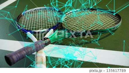 Pair of tennis rackets lying crossed over boundary line on court, with neon teal network overlay Pair of tennis rackets lying crossed over boundary line on court, with neon teal network overlay 135617789