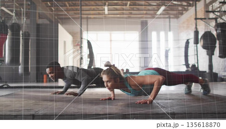 Performing push-ups workout partners wearing sportswear on rubber mat in gym, with punching bags Performing push-ups workout partners wearing sportswear on rubber mat in gym, with punching bags 135618870