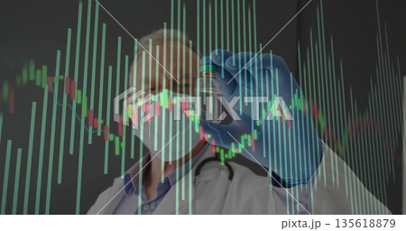 Holding vial, senior doctor wearing protective gear and stethoscope in lab, with data chart overlay Holding vial, senior doctor wearing protective gear and stethoscope in lab, with data chart overlay 135618879