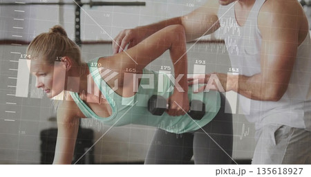 Lifting mid adult woman doing bent-over dumbbell row in gym with racks, displaying biometric graphs Lifting mid adult woman doing bent-over dumbbell row in gym with racks, displaying biometric graphs 135618927