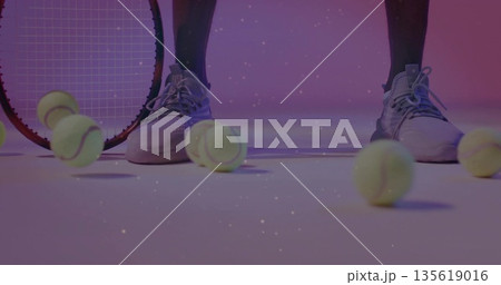 Showing lower legs of tennis player standing on studio floor, with tennis balls, racket and shoes 135619016