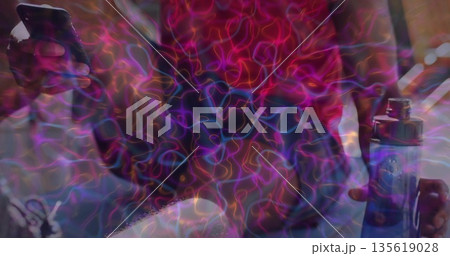 Sitting man wearing red top holding smartphone and blue vape device on couch, neon light trails Sitting man wearing red top holding smartphone and blue vape device on couch, neon light trails 135619028