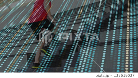 Climbing athlete wearing red shirt ascending in stairwell with glass panels and digital dot overlay 135619037