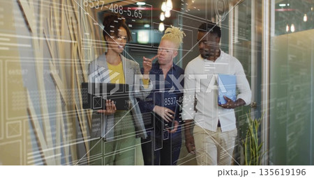 3 professionals in suits walking office corridor reviewing UI overlays, with laptop tablet notebook 135619196
