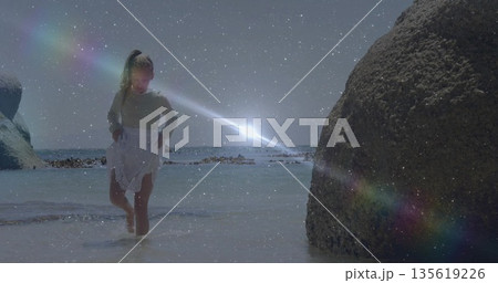 Walking child wearing white skirt through shallow seawater at rocky beach, with sunset lens flares Walking child wearing white skirt through shallow seawater at rocky beach, with sunset lens flares 135619226