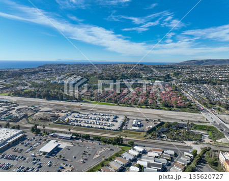 Aerial view over San Juan Capistrano, California, featuring the historic mission, library, sports courts, and an Amtrak train pulling into the downtown station. 135620727