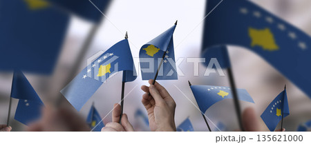 Kosovo flags in their hands on a blurred urban background 135621000