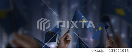 Kosovo flags in their hands on a blurred urban background 135621018