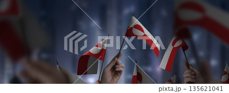 Greenland flags in their hands on a blurred urban background 135621041