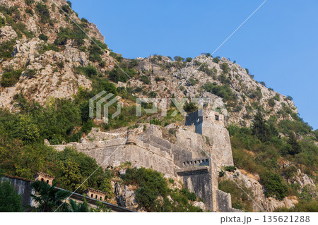 Montenegro, Kotor. Rugged mountain fortress ruins cling to a rocky hillside Montenegro, Kotor. Rugged mountain fortress ruins cling to a rocky hillside 135621288
