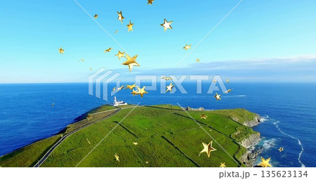 Capturing headland over blue ocean, with winding road leading to white lighthouse and golden stars 135623134