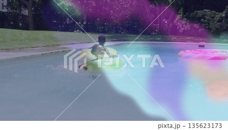 Floating siblings wearing swimsuit and trunks in backyard pool, with green, yellow inflatable rings Floating siblings wearing swimsuit and trunks in backyard pool, with green, yellow inflatable rings 135623173