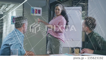 Presenting designer in pink sweater pointing color swatches in office, with flip chart and papers Presenting designer in pink sweater pointing color swatches in office, with flip chart and papers 135623192